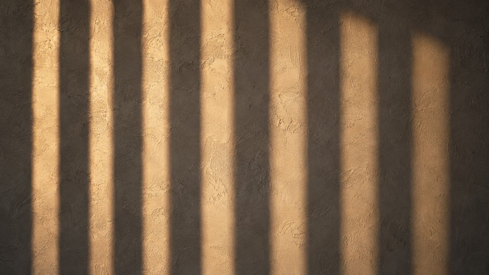 Stripes of light and shadow across a warm plaster wall